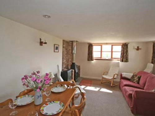 een woonkamer met een tafel en een bank bij Barrowmead Cottage - E2377 in Banwell