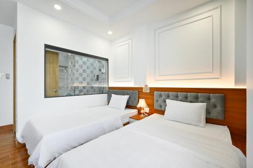 two beds in a room with white walls at Lotus Airport Hotel Saigon in Ho Chi Minh City