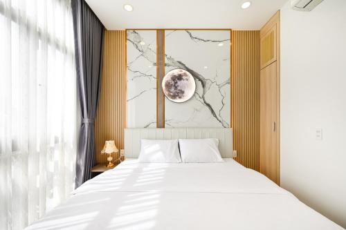 a bedroom with a white bed and a painting of a moon at Lotus Airport Hotel Saigon in Ho Chi Minh City