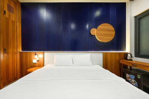 a bedroom with a large white bed and a blue wall at Lotus Airport Hotel Saigon in Ho Chi Minh City