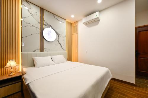 a bedroom with a white bed and a clock on the wall at Lotus Airport Hotel Saigon in Ho Chi Minh City