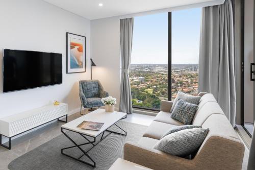 a living room with a couch and a large window at Meriton Suites George Street, Parramatta in Sydney