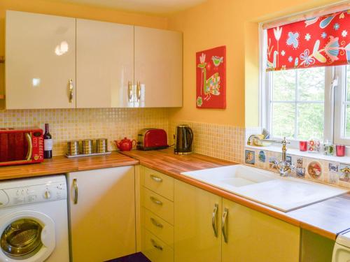 een keuken met een wastafel en een wasmachine bij The Shepherds Bothy in Tetford
