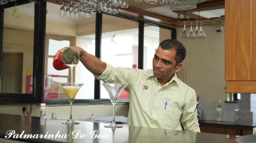 a man mixing a drink in a martini glass at Palmarinha de Goa in Calangute