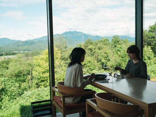 two women sitting at a table in front of a window at SNOW PEAK FIELD SUITE SPA HEADQUARTERS in Morimachi