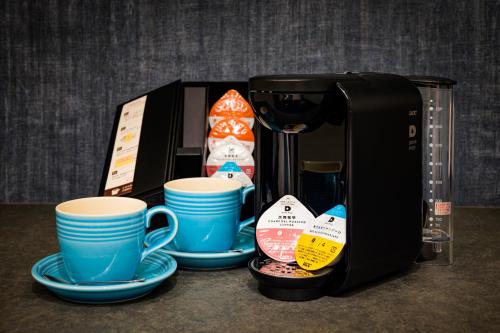 a coffee maker with cups and plates on a counter at Hotel WILL BASE 鶴見 in Yokohama