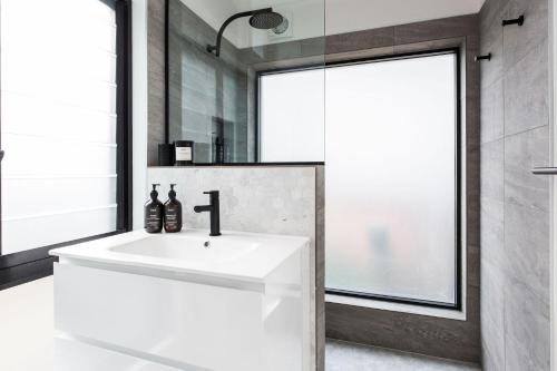 a bathroom with a white sink and a mirror at The Coconut Palm One is a designer Villa in Sunshine Beach