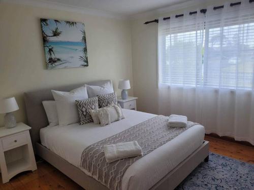 een witte slaapkamer met een bed en een raam bij Sunset Lake View in Windang