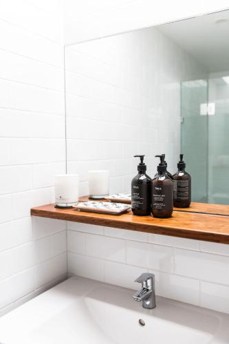 a bathroom with a shelf with three bottles of soap at The Coconut Palm TWO in Sunshine Beach