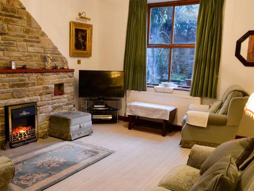 a living room with a fireplace and a tv at The Garden Cottage in Skipton