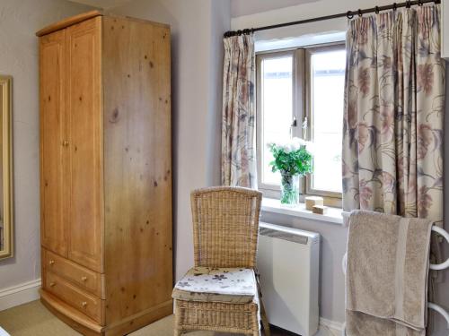 a room with a chair and a cabinet and a window at The Blacksmiths Shop in Lanlivery