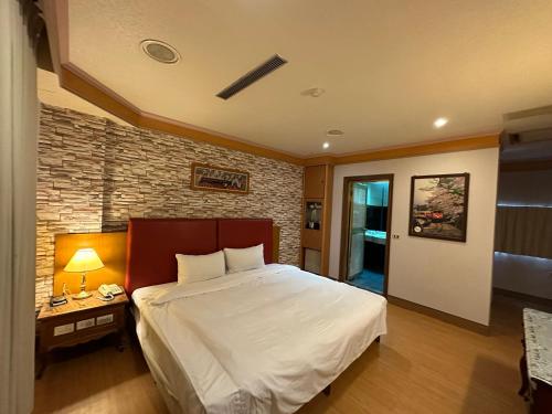 a bedroom with a large bed and a brick wall at Wenpin Hotel - Pier 2 in Kaohsiung