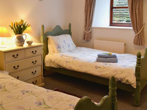 a bedroom with two beds and a dresser at The Linhay in Trewen