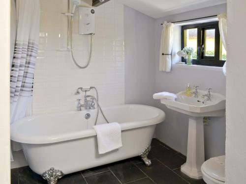 Baño blanco con bañera y lavamanos en Bee Bowl Cottage - Httd, en Bideford