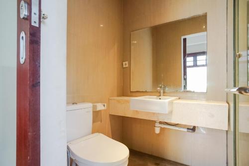 a bathroom with a toilet and a sink and a mirror at Akarsa Transit in Sanur