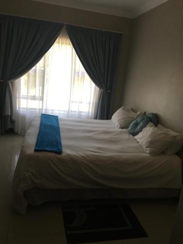een bed met een blauwe handdoek voor een raam bij Durban luxury accommodation in Pinetown