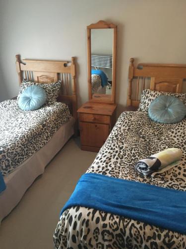 een slaapkamer met 2 bedden met blauwe kussens en een spiegel bij Durban luxury accommodation in Pinetown