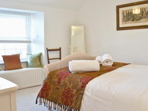 a bedroom with a bed with two towels on it at Bucca Cottage in Newlyn