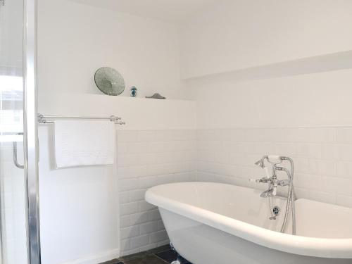 a white bathroom with a tub and a shower at Bucca Cottage in Newlyn