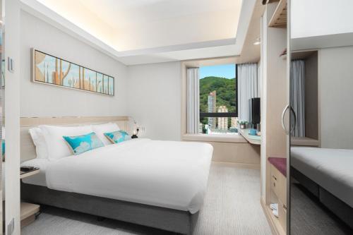 a bedroom with a large white bed and a window at Metaplace Hotel in Hong Kong