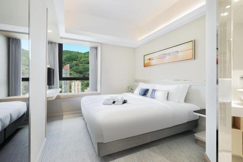 a hotel room with a large white bed and a bathroom at Metaplace Hotel in Hong Kong