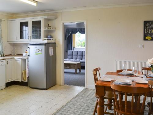 eine Küche und ein Esszimmer mit einem Tisch und einem Kühlschrank in der Unterkunft Glebe Farm Bungalow in Market Rasen