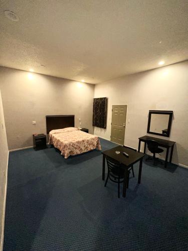 een slaapkamer met een bed, een tafel en een bureau bij Tropic West Motel in Bell