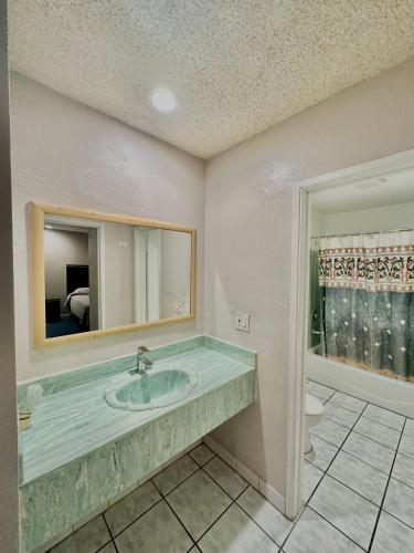 ein Bad mit einem Waschbecken und einem Spiegel in der Unterkunft Tropic West Motel in Bell