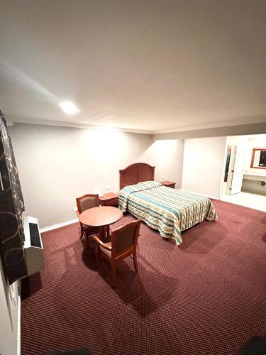 um quarto de hotel com uma cama, uma mesa e cadeiras em Tropic West Motel em Bell