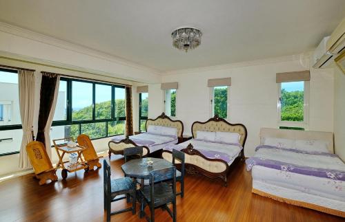 a bedroom with two beds and a table and windows at Qixingtan Hai Wan B&B in Dahan