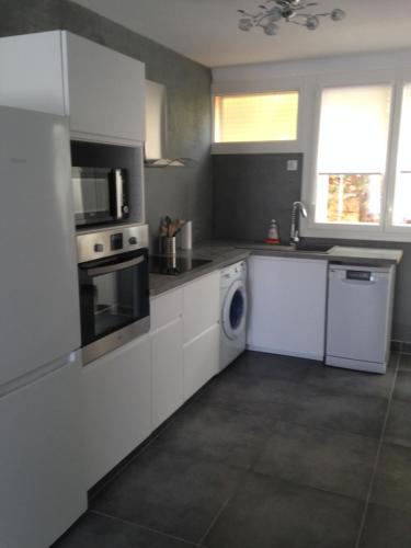 une cuisine avec des armoires blanches et une laveuse et une sécheuse dans l'établissement T3 centre de Cassis parking, climatisé, wifi, à Cassis