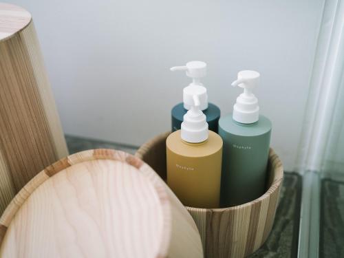 two bottles ofodorizers in a wooden container next to a basket at SNOW PEAK FIELD SUITE SPA HEADQUARTERS in Morimachi