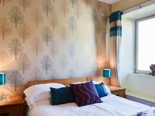 Un dormitorio con una cama y una pared con árboles. en Meadowbank Lodge, en Staveley