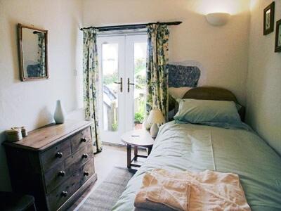 a bedroom with a bed and a dresser and a window at Porth Nanven Barn in St Just