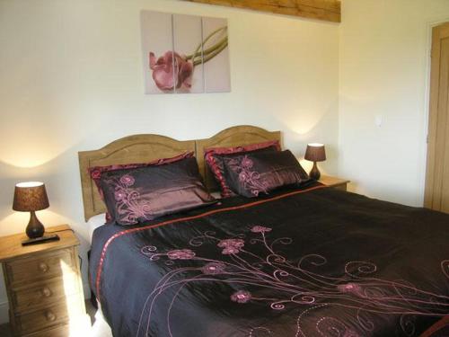 a bedroom with a bed with purple sheets and pillows at Bramble Cottage in Ripley