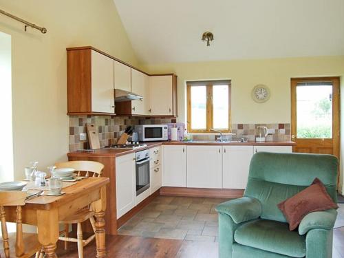 a kitchen with a couch and a table and a chair at Bramble Cottage in Ripley