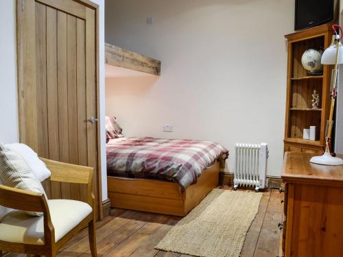 a bedroom with a bed and a chair and a desk at Grooms Room in Aberdare
