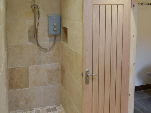 um chuveiro com uma porta de madeira na casa de banho em The Dairy em Beck Hole