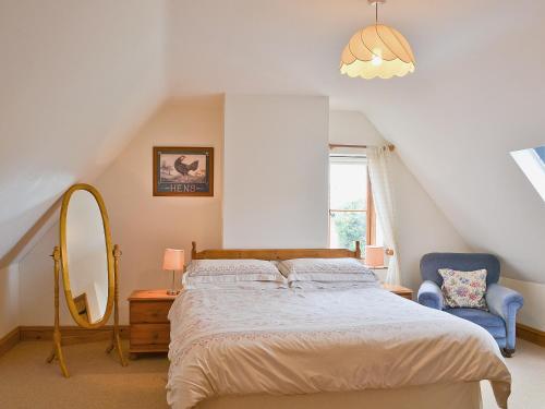 - une chambre avec un lit, un miroir et une chaise dans l'établissement Copper Cottage, à Burgh Saint Peter