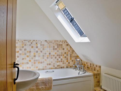 a bathroom with a bath tub and a skylight at Copper Cottage in Burgh Saint Peter