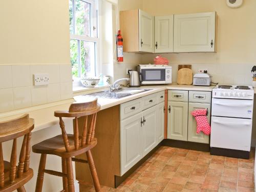 a kitchen with white cabinets and a stove top oven at Berrymoor Farm Cott in Kirkoswald