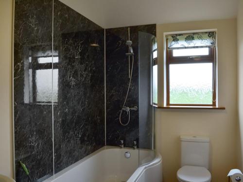 a bathroom with a tub and a toilet and a window at Mill Stone Cottage - E5423 in Chapel Saint Leonards