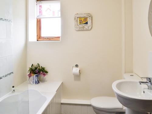 a white bathroom with a toilet and a sink at The Cart Shed - E1768 in Westleton