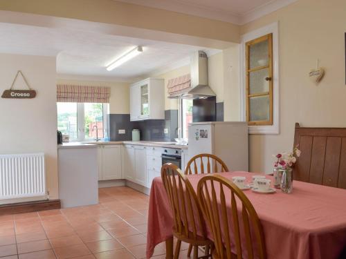 una cocina con una mesa con un mantel rojo. en Middleton Cottage en Llanddarog