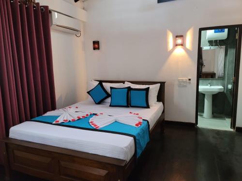 a bedroom with a bed with red sheets and a sink at Shima Guni Beach Club Hotel in Matara