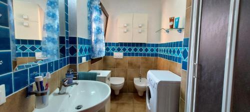 baño de azulejos azules con lavabo y aseo en Casa giardino e barbecue en Castelsardo