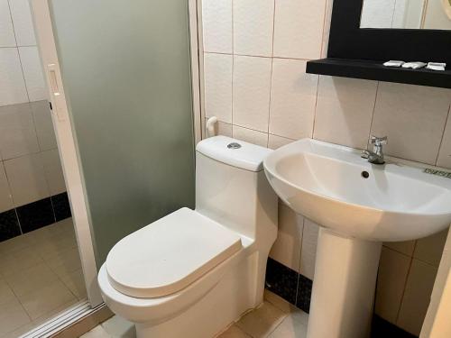 a bathroom with a white toilet and a sink at Hotel Benjamin Naval in Naval