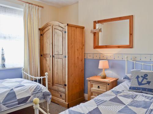 a bedroom with a bed and a dresser and a mirror at Coble Cottage - 28317 in Flamborough