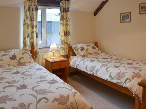 a bedroom with two beds and a window at Haycombe Cottage in Camelford