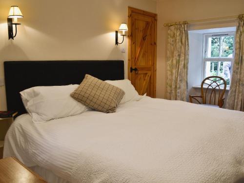 a bedroom with a bed with white sheets and a window at Jocky Milnes Croft in Haugh of Glass